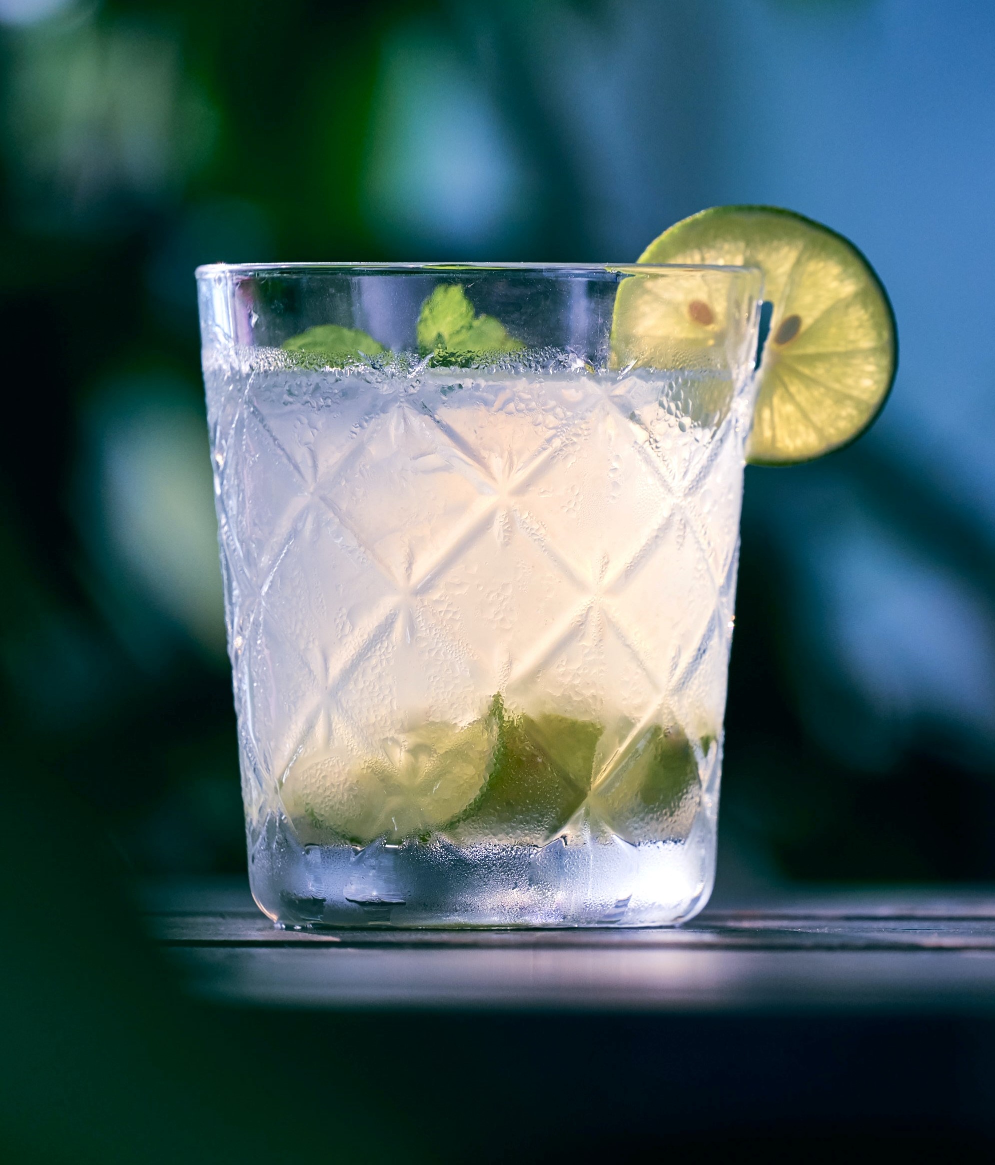 A small glass with clear liquid in it (rum and sugar) and lemons